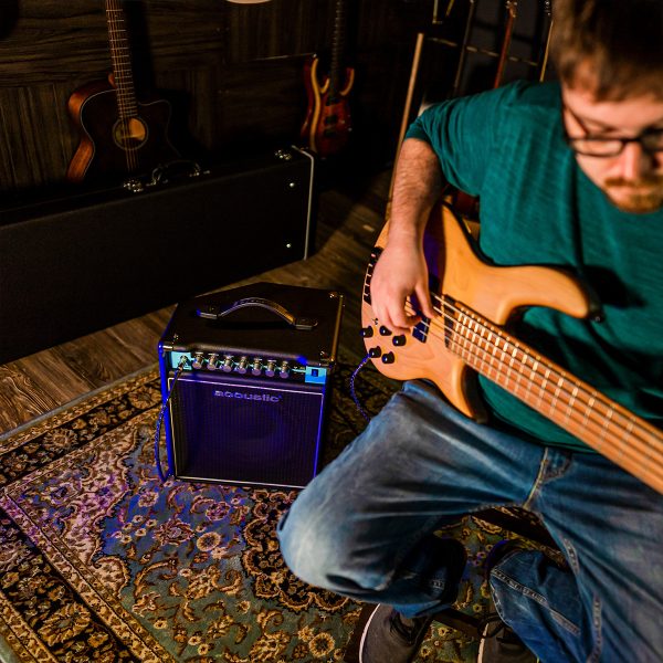 B25C combo bass amp played by a bass guitar player with guitars and guitar cases behind