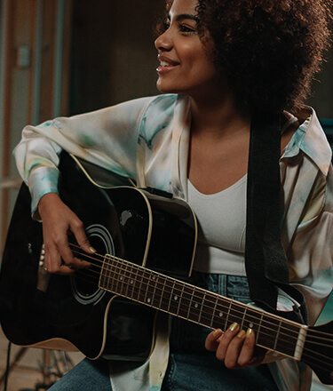 female acoustic guitar player strumming black acoustic guitar